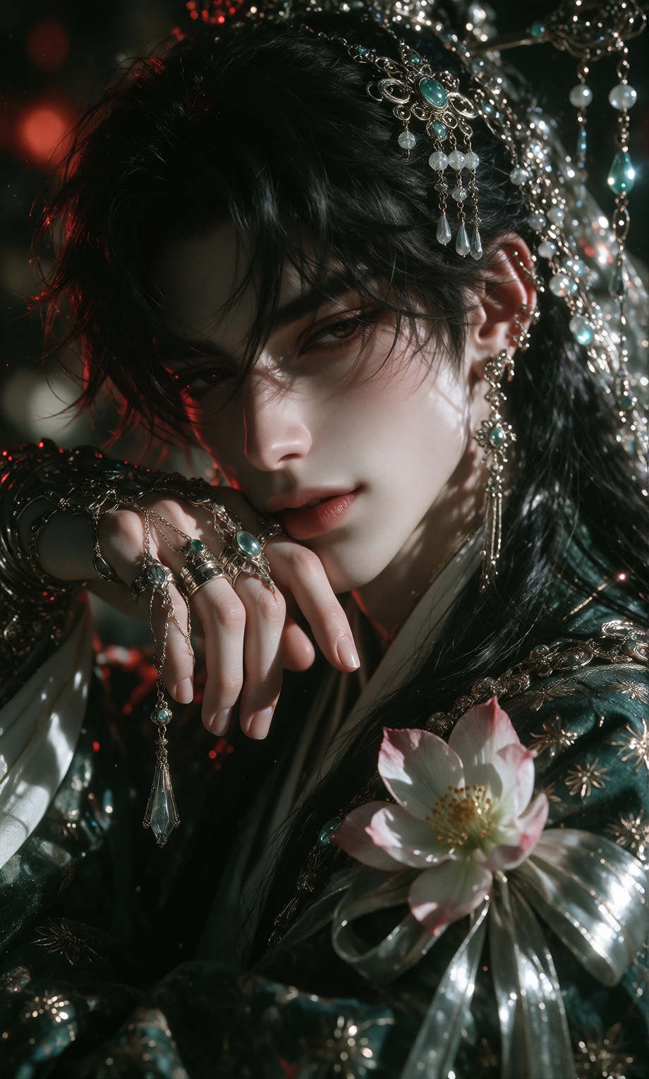A pale-skinned male with long black hair partially obscuring his face rests his chin on a hand adorned with delicate silve...