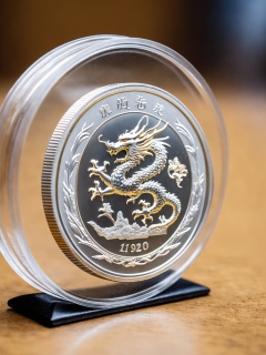 a photo, a sliver coin, 1 oz sliver coin,( in a display case:1.2), close up, a sliver coin with a dragon on it, blurry simple background,