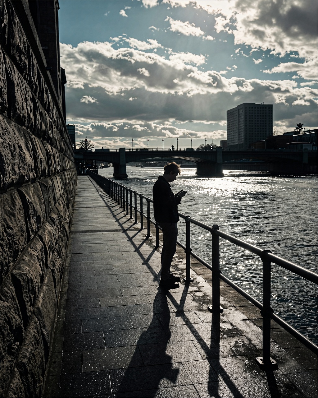 A moody urban waterfront scene captured in a cinematic high contrast style with a desaturated teal and gray color palette....