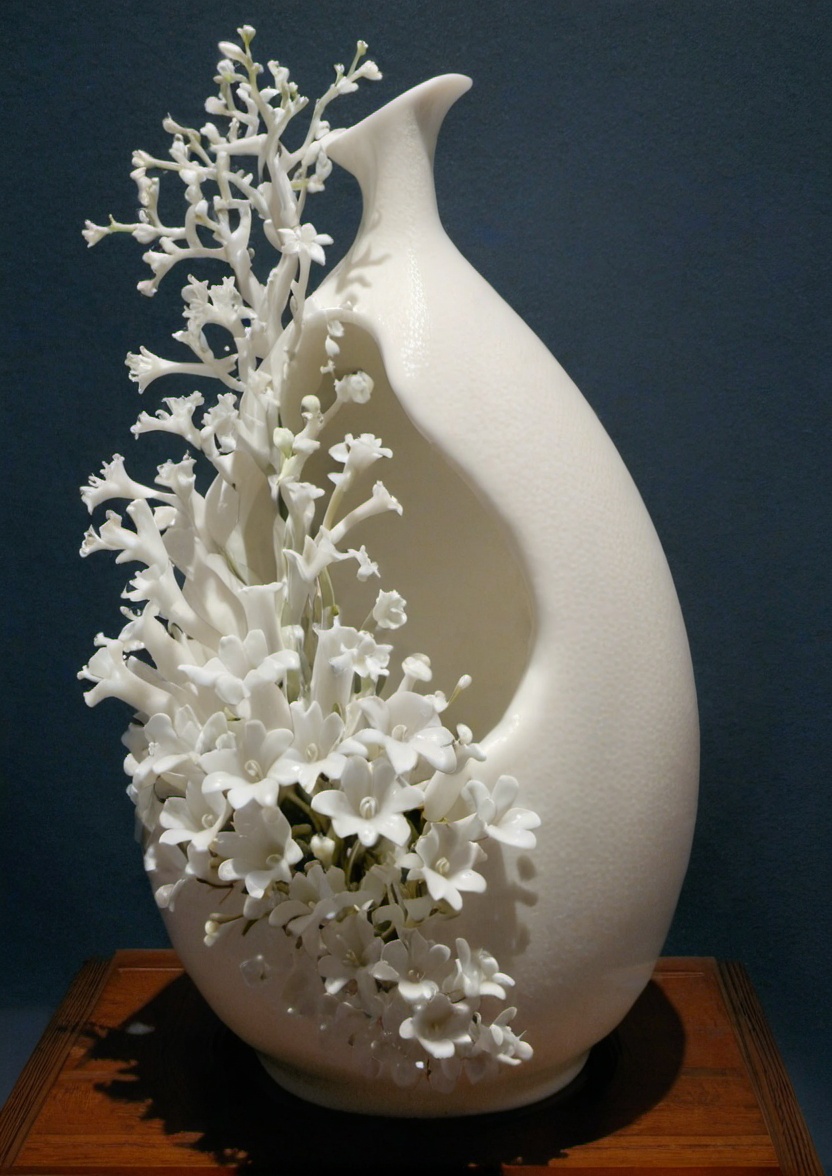 dehuabaici,puregirl<lora:dehuabaiciSDXL-000011:0.85> <lora:puregirl-000007:0.15>A white porcelain of a vase with a large opening on one side, with many small white flowers growing out of the opening. The vase is sitting on a wooden surface, with a dark blue background.