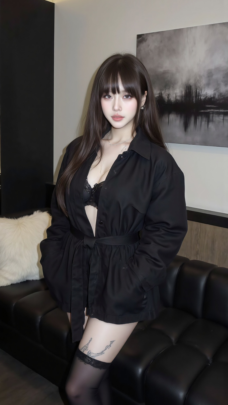 in detail. This photograph captures a young woman with long,straight brown hair and bangs,standing in a modern,minimalist interior setting. She has a fair complexion and a delicate,youthful facial structure with large,expressive eyes,full lips,and a slight pout. Her outfit consists of a black,oversized trench coat with a high collar,which is cinched at the waist with a belt,revealing a black bra underneath. She is wearing black leggings,and her left thigh features a tattoo of delicate,flowing lines. The background includes a black sofa with a plush,white pillow,and a wall adorned with a large,abstract artwork in shades of gray and black. The room has a sleek,contemporary design,with clean lines and neutral tones. The overall atmosphere is modern and chic,with a touch of edgy fashion.,