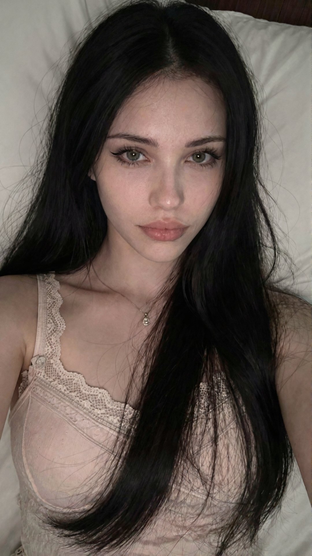 L1n4 with long black hair is shown in a close-up selfie. She appears to be lying down on a light-colored pillow,  the came...