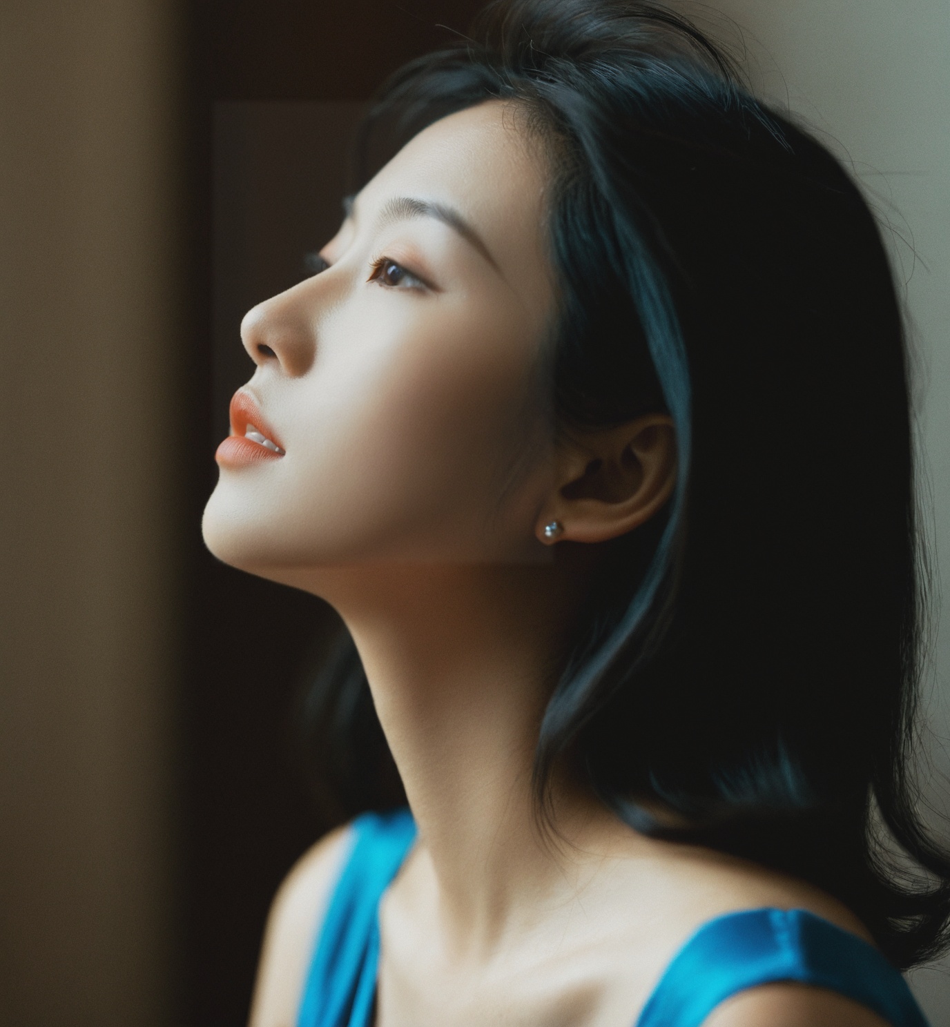 ,woman,Asian ethnicity,profile view,natural light,indoor setting,soft focus,moody,side lighting,contemplative expression,hair clip,blue dress,subtle makeup,young *****,serene,shadows,warm tones,1girl,solo,realistic,closed eyes,blurry,black hair,blurry background,closed mouth,photorealistic,lips,collarbone,upper body,portrait,depth of field,nose,<lora:15-000008:0.6>