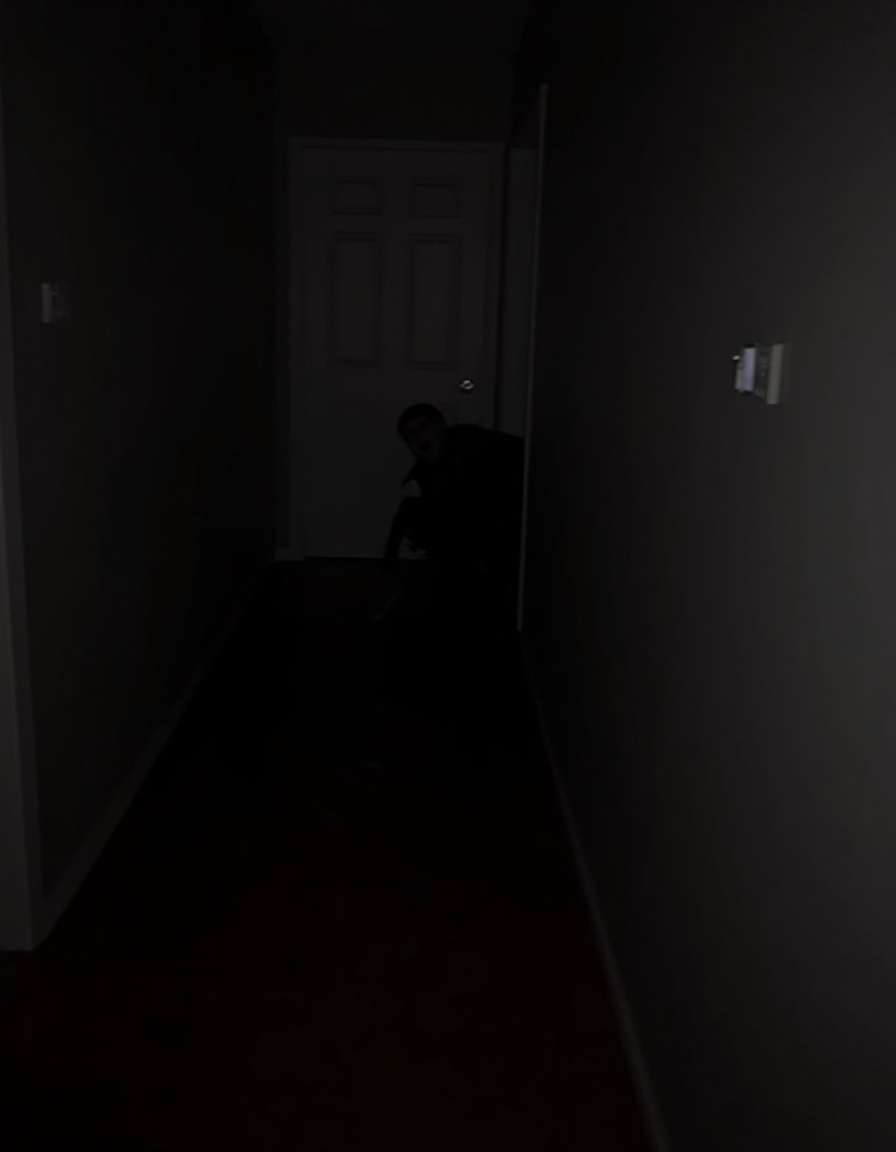 the image shows a dark hallway with a white door on the right side, on the left side of the image, there is a person crouching down on the floor, holding a knife in their hand, the person appears to be in a state of panic or fear, with their eyes wide open and their mouth slightly open, the hallway is dimly lit, with only a small amount of light coming from the door, the walls are painted in a dark color, and the floor is made of wood, the image is taken from a low angle, looking up at the person,<lora:majichorror_flux:1>,