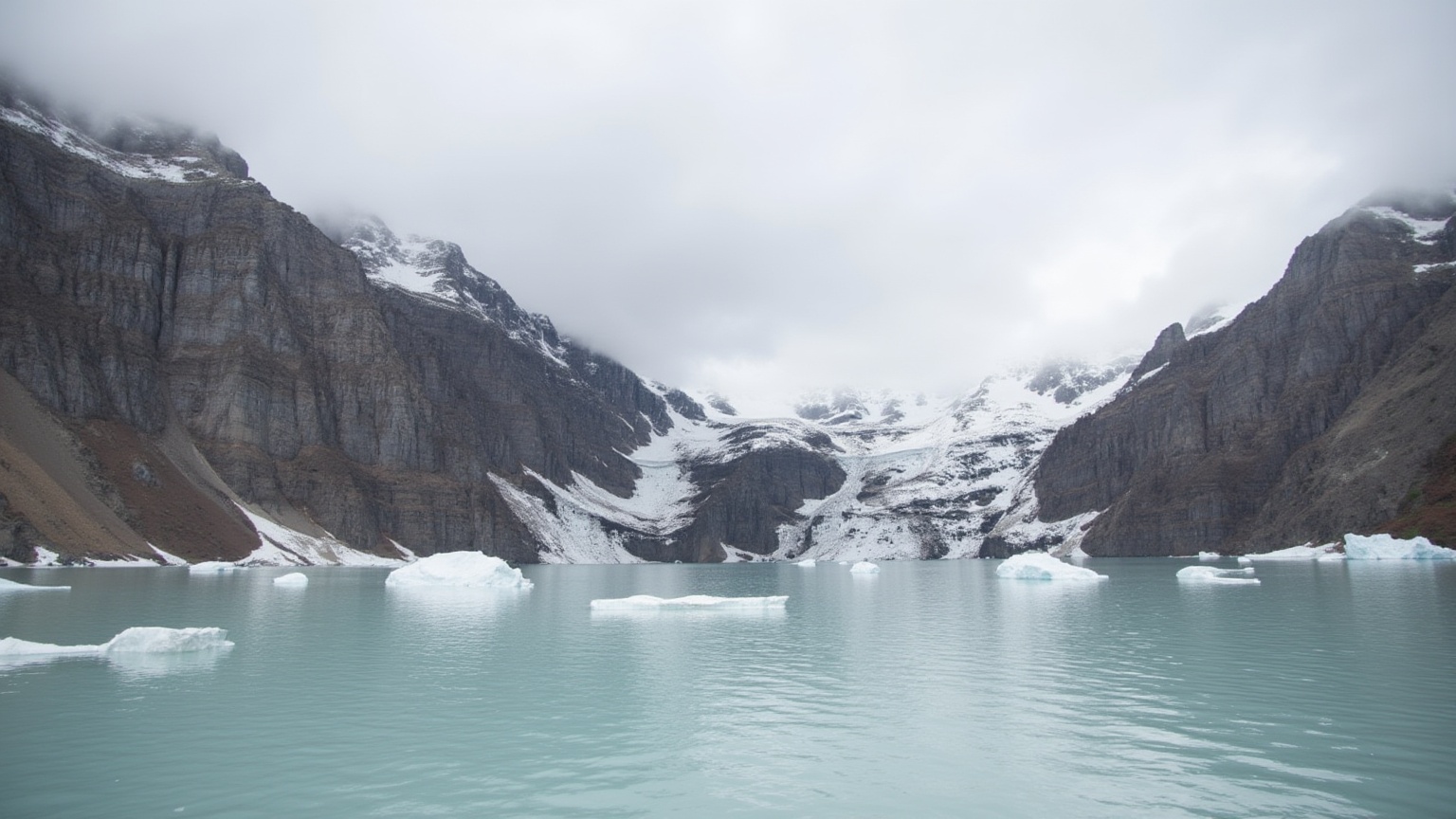 This is a high-resolution photograph capturing a serene alpine lake nestled within a rugged mountainous landscape. The lak...
