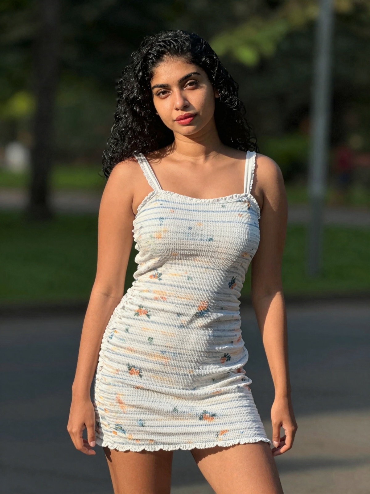 gorgeous woman in her 30s in a cute mini summer dress posing for a sensual photography session at a local park,  Mobile ph...