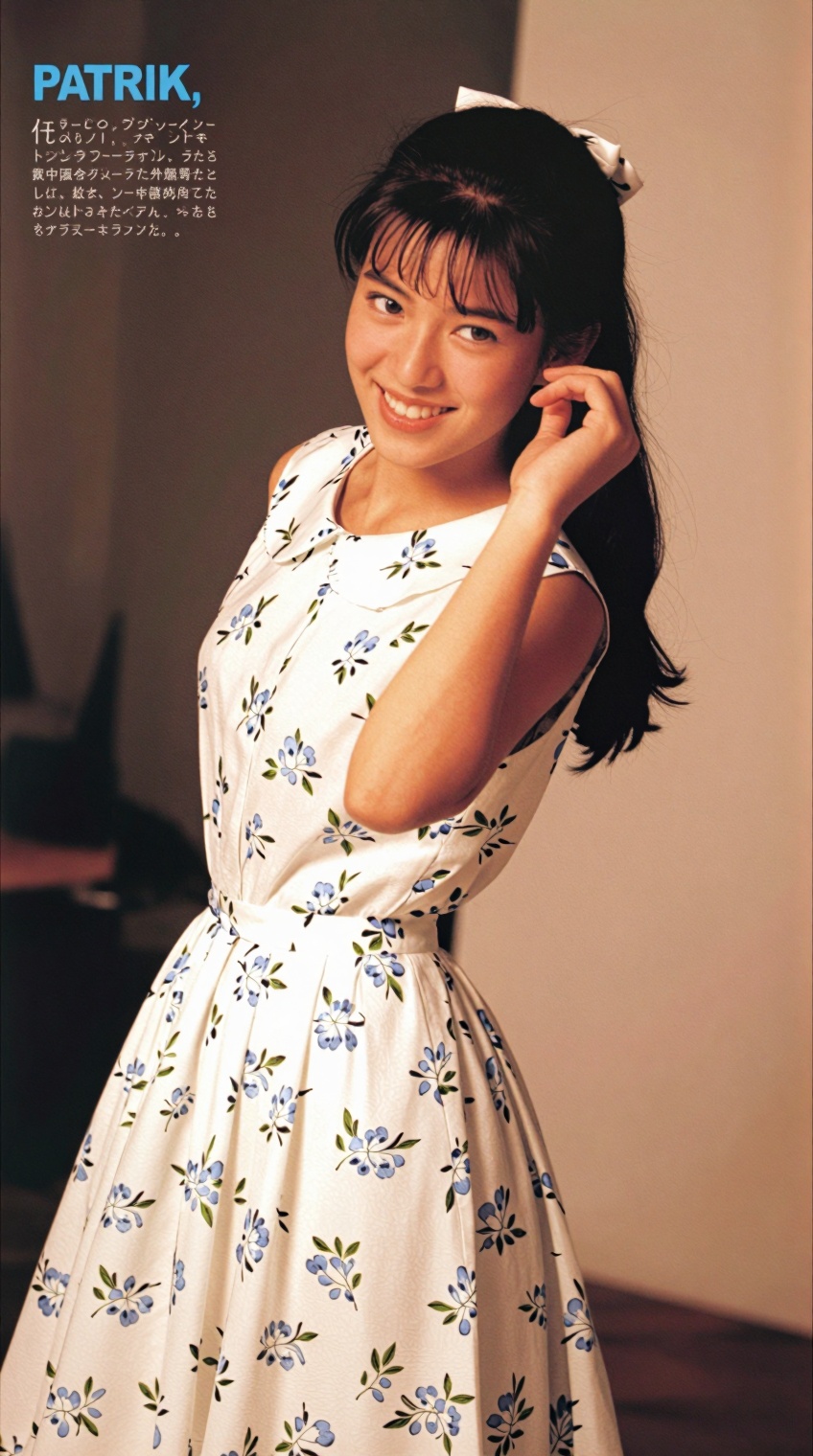 A young woman with dark hair tied back and a small white bow smiles warmly while glancing over her shoulder,  her right ha...