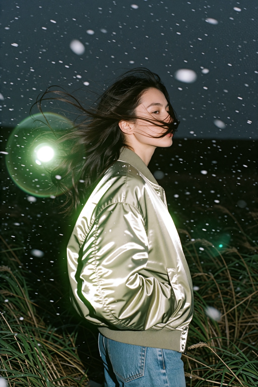 An experimental analog film snapshot of a young woman standing in a grassy field at night under a dark twilight sky. Captu...