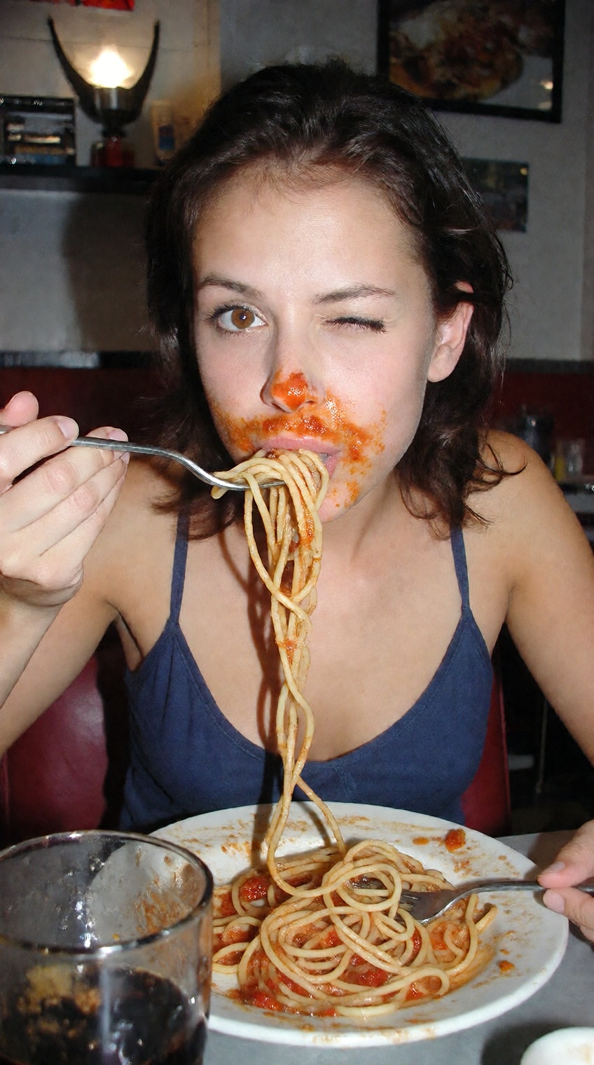 A funny and playfully teasing 2000s digicam photo capturing a candid moment at a diner. A beautiful 22-year-old woman with...