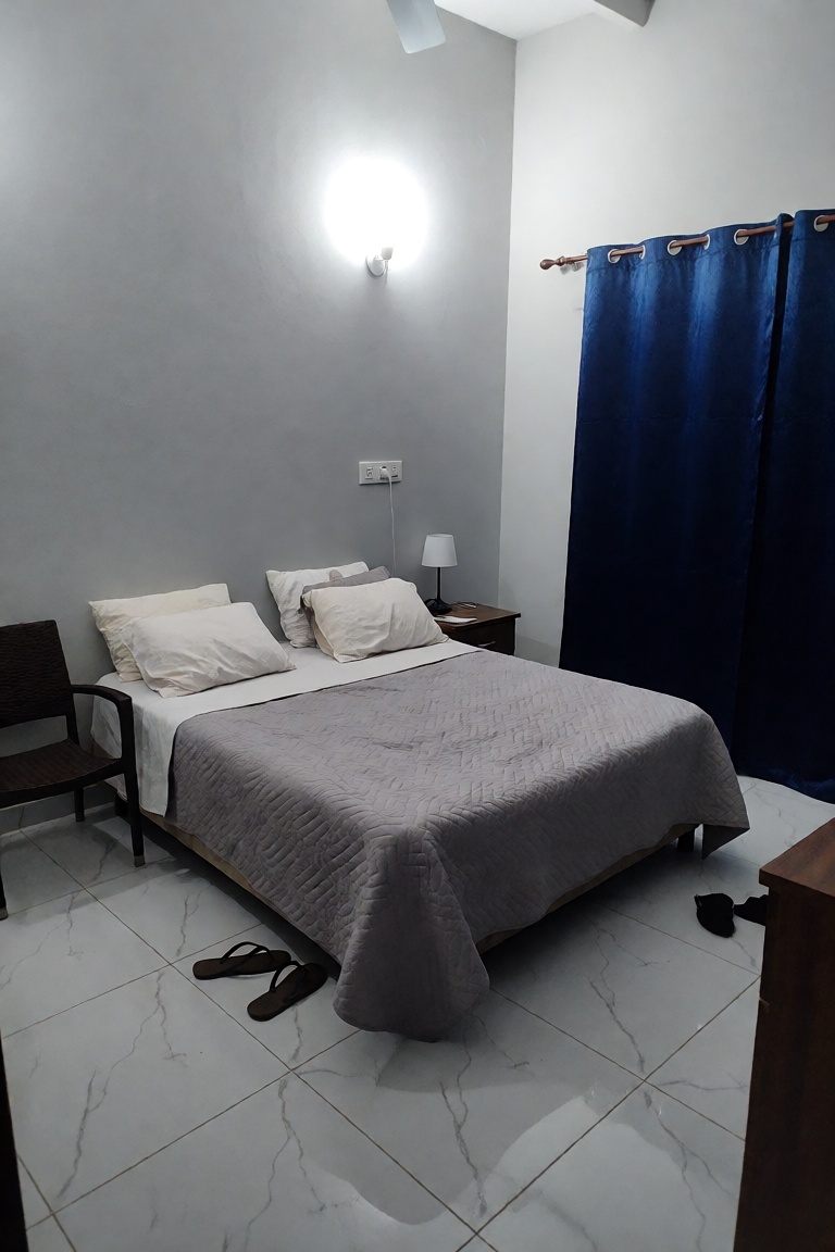 A modern,  minimalist bedroom interior featuring a queen-sized bed as the central focus,  dressed in a light grey quilted...