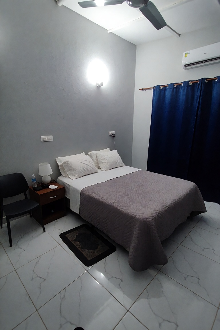 A minimalist,  functional hotel bedroom illuminated by a bright,  warm wall-mounted light and a ceiling fixture on Tensor.Art