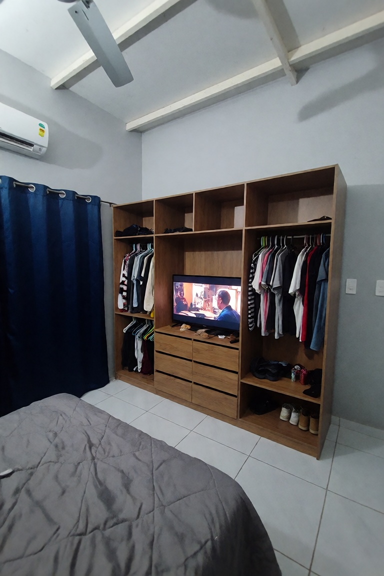 A high-angle interior shot of a modern,  minimalist bedroom featuring a large,  multi-functional wooden wardrobe unit that...