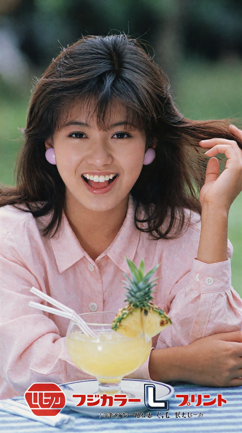 A young woman with shoulder-length brown hair and bangs smiles warmly at the camera,  her right hand gently lifting a stra...