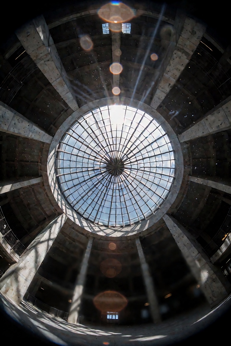 An immersive ultra-wide-angle 15mm fisheye photograph captured from the center floor of a massive,  circular concrete libr...