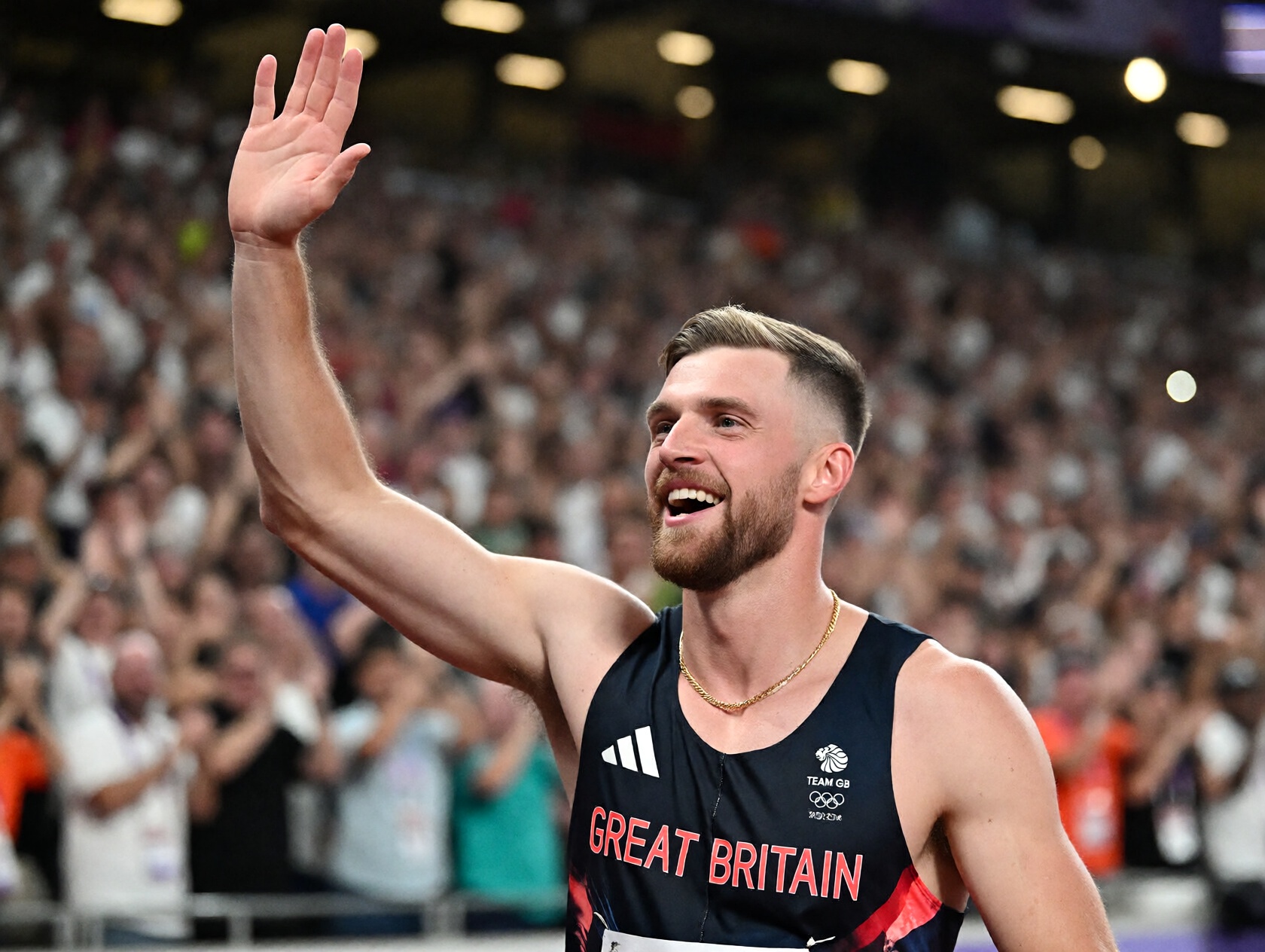 {"high_level_description":"A triumphant male Olympic athlete for Team Great Britain waves to a cheering crowd under bright...