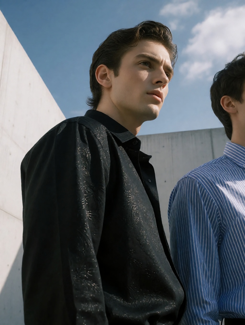 A high-end fashion editorial low-angle photo captures two handsome young men outdoors,  their forms sharply defined agains...