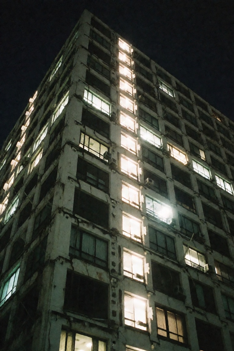 A photo shot on 35mm film from below of a super tall and huge old japanese building at night with cross lighting across th...
