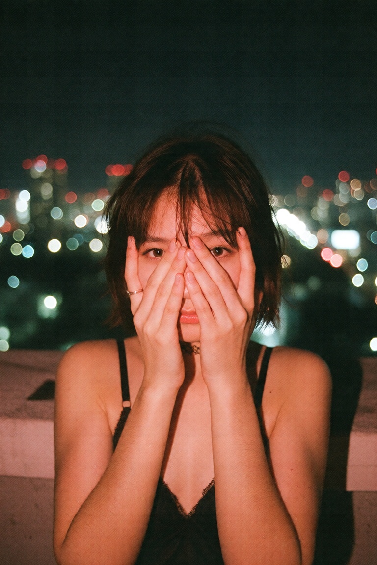 A portrait photo shot on 35mm film of a Japanese idol with short hair wearing a choker and a black **** top ,  coveri6her...