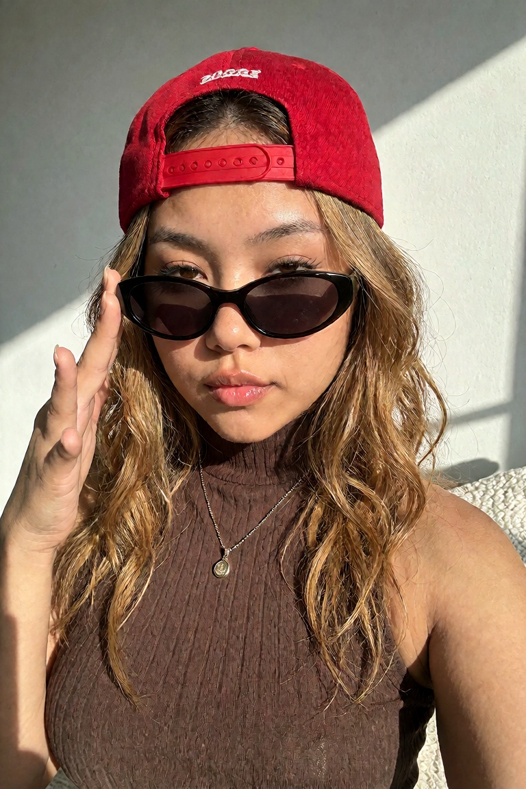 A vibrant,  close-up portrait of a stylish East Asian woman with wavy,  golden-brown hair posing under bright on Tensor.Art