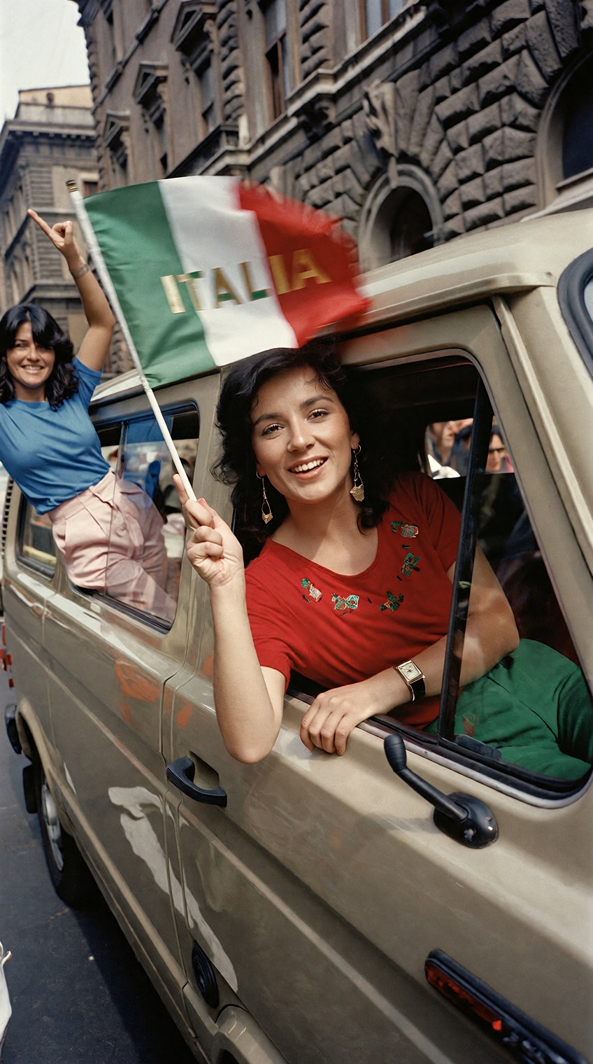 @charleshtraub,  A smiling woman leans out the front window of a beige van,  waving a small Italian flag. She wears a red...