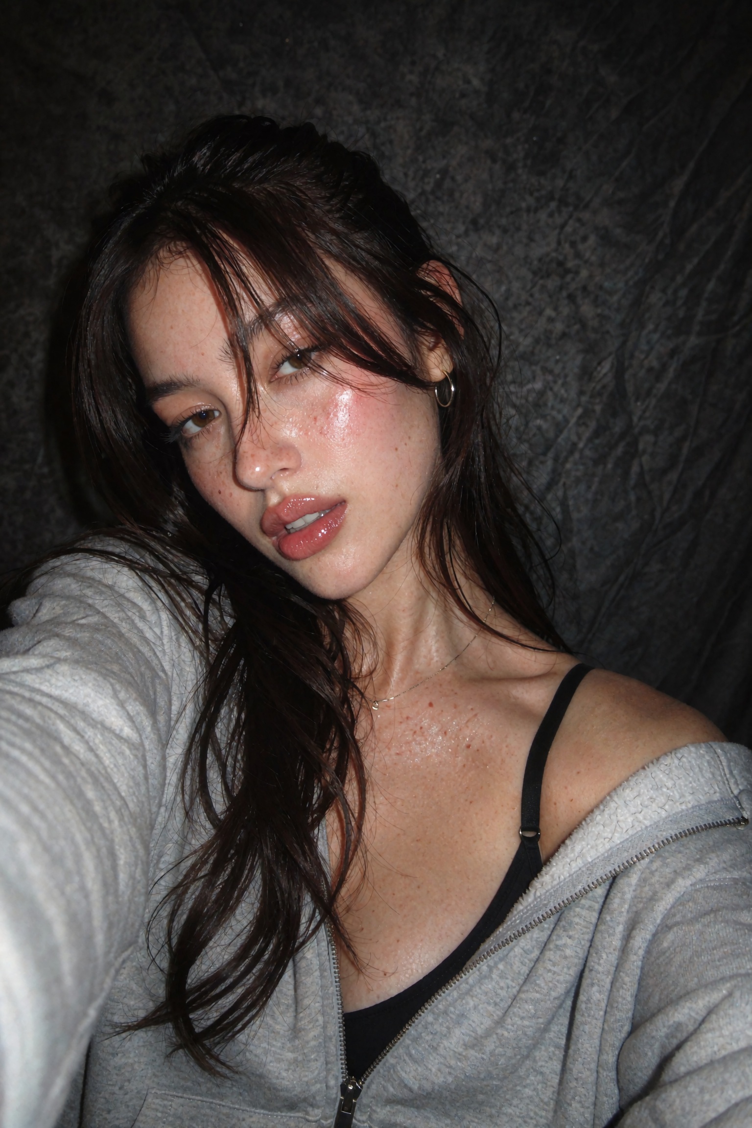 Candid documentary-style UGC smartphone flash selfie of a young woman,  close-up framing cropped at the chest,  head tilte...