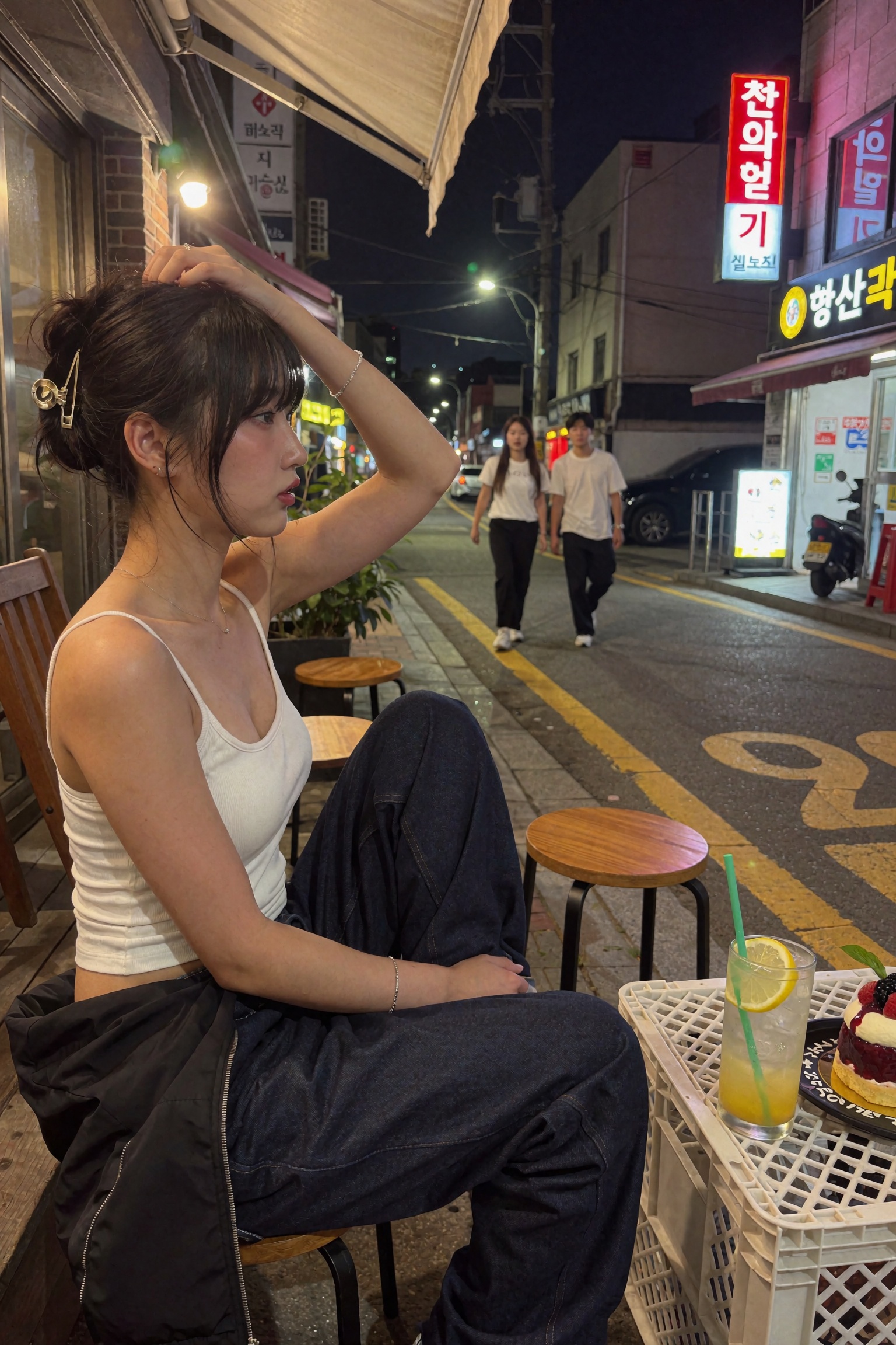 Candid documentary-style UGC smartphone snapshot of a young woman seated in profile at outdoor street-side seating on a Ko...
