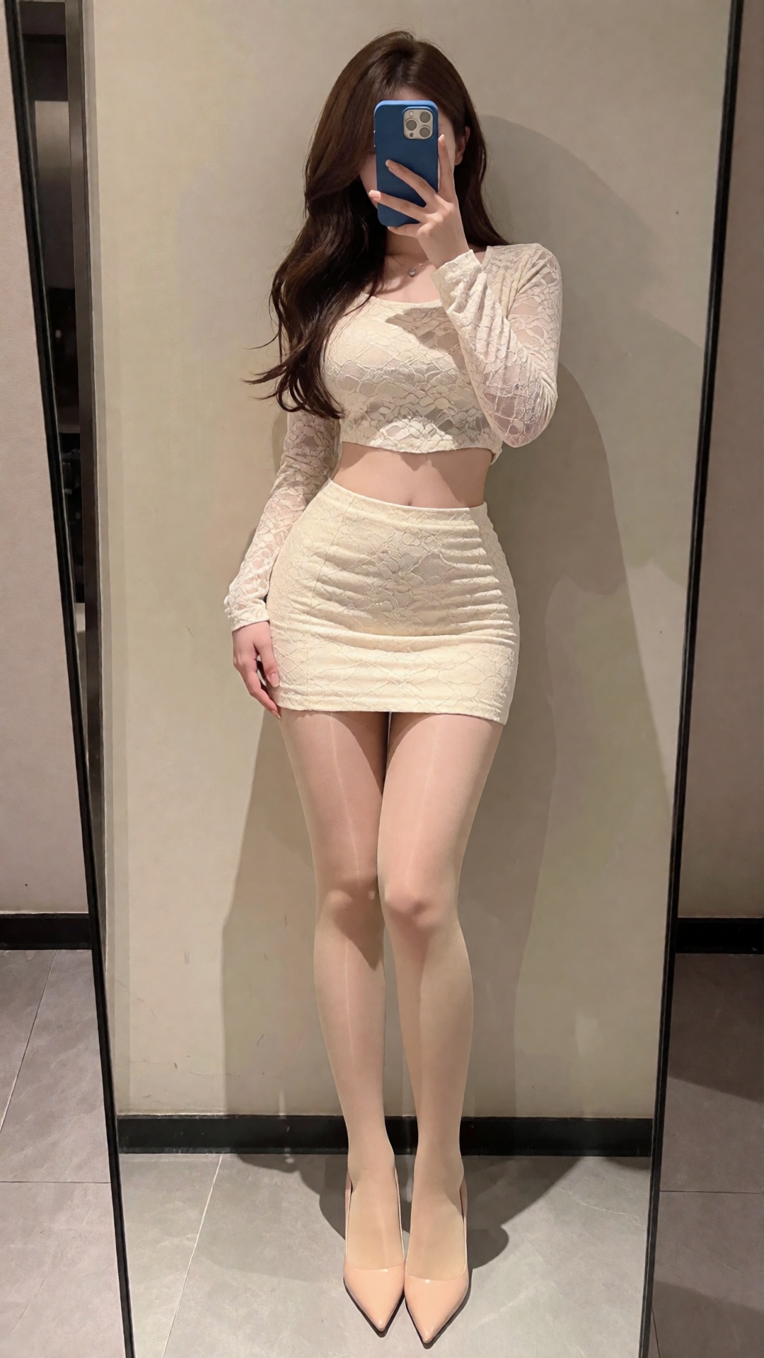 Photograph of a young woman taking a mirror selfie. She has long,  wavy brown hair and is wearing a tight,  cream-colored...