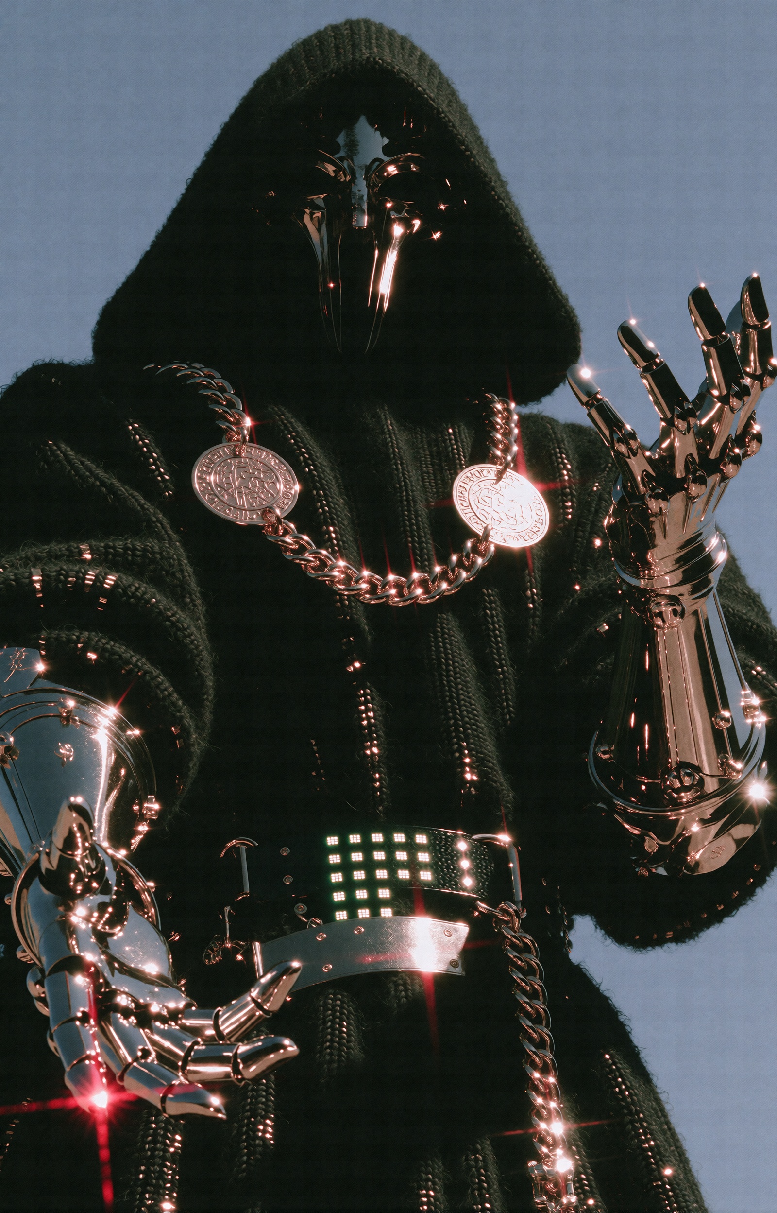 An imposing hooded figure stands with arms outstretched wide in a grand messianic gesture,  open palms turned upward. A vo...