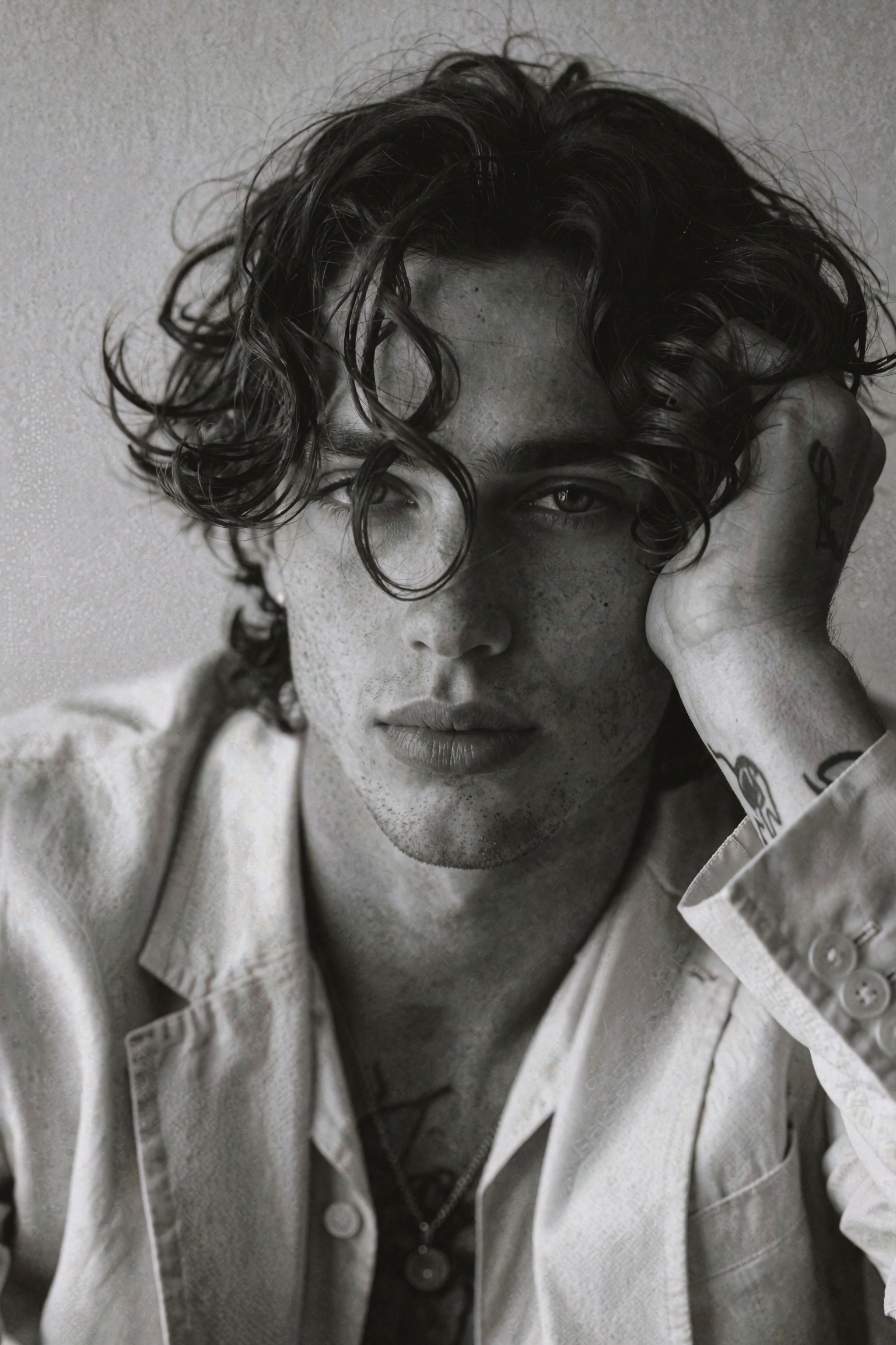 Cinematic classic monochrome editorial portrait of a young man in a tight close-up composition,  head tilted slightly and...
