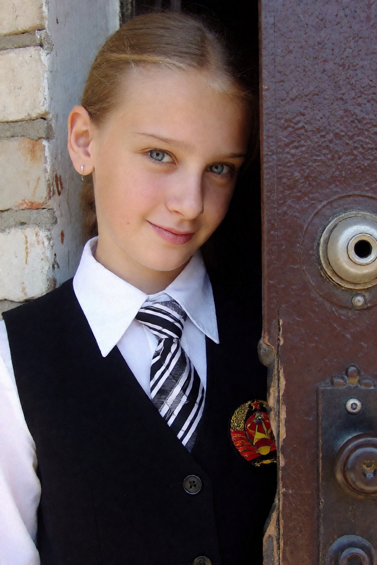 candid close up photo of a girl wearing a soviet school uniform,  she is standing beside her apartment frontdoor on Tensor...