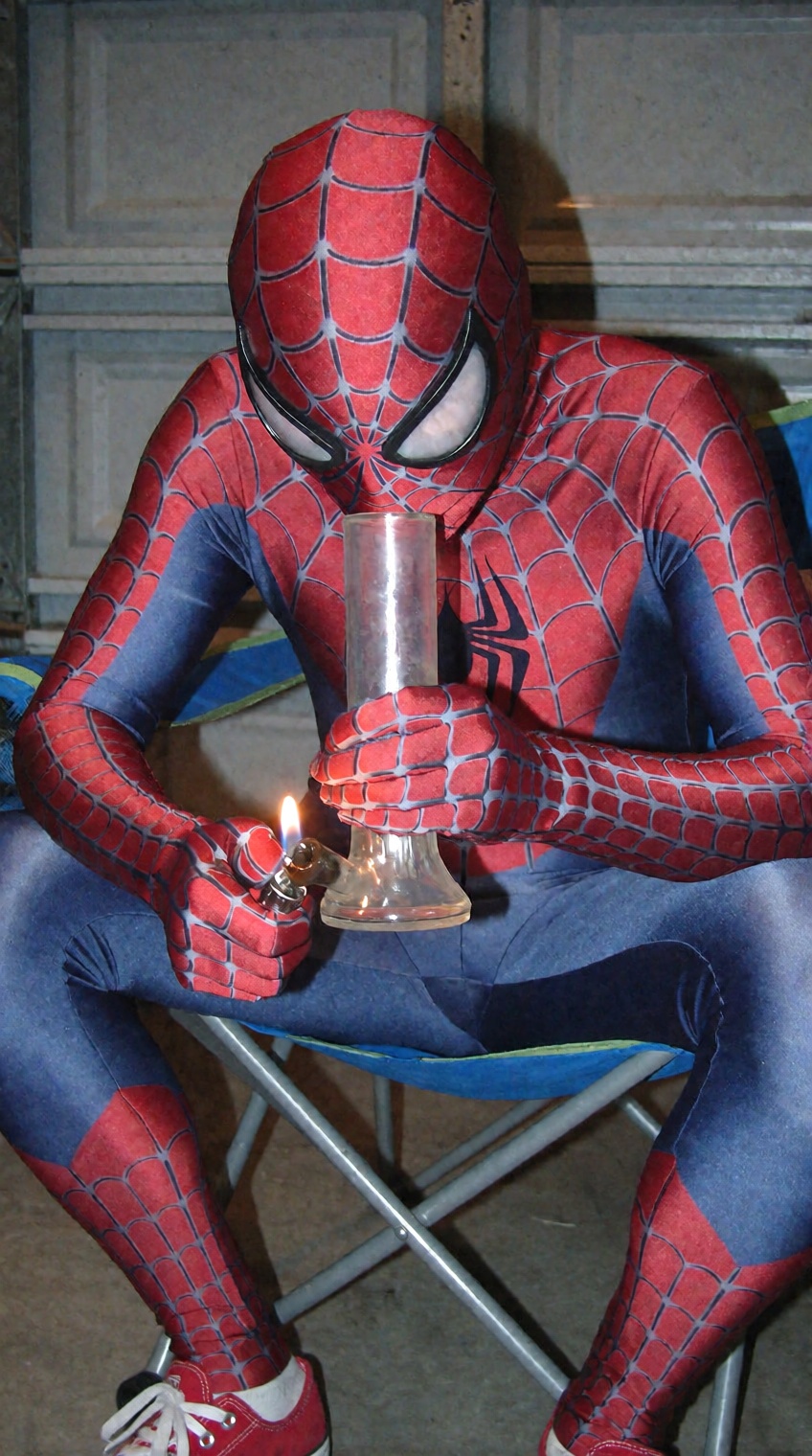 A surreal candid snapshot of a person dressed in a full red and blue webbed superhero bodysuit,  sitting slumped forward i...