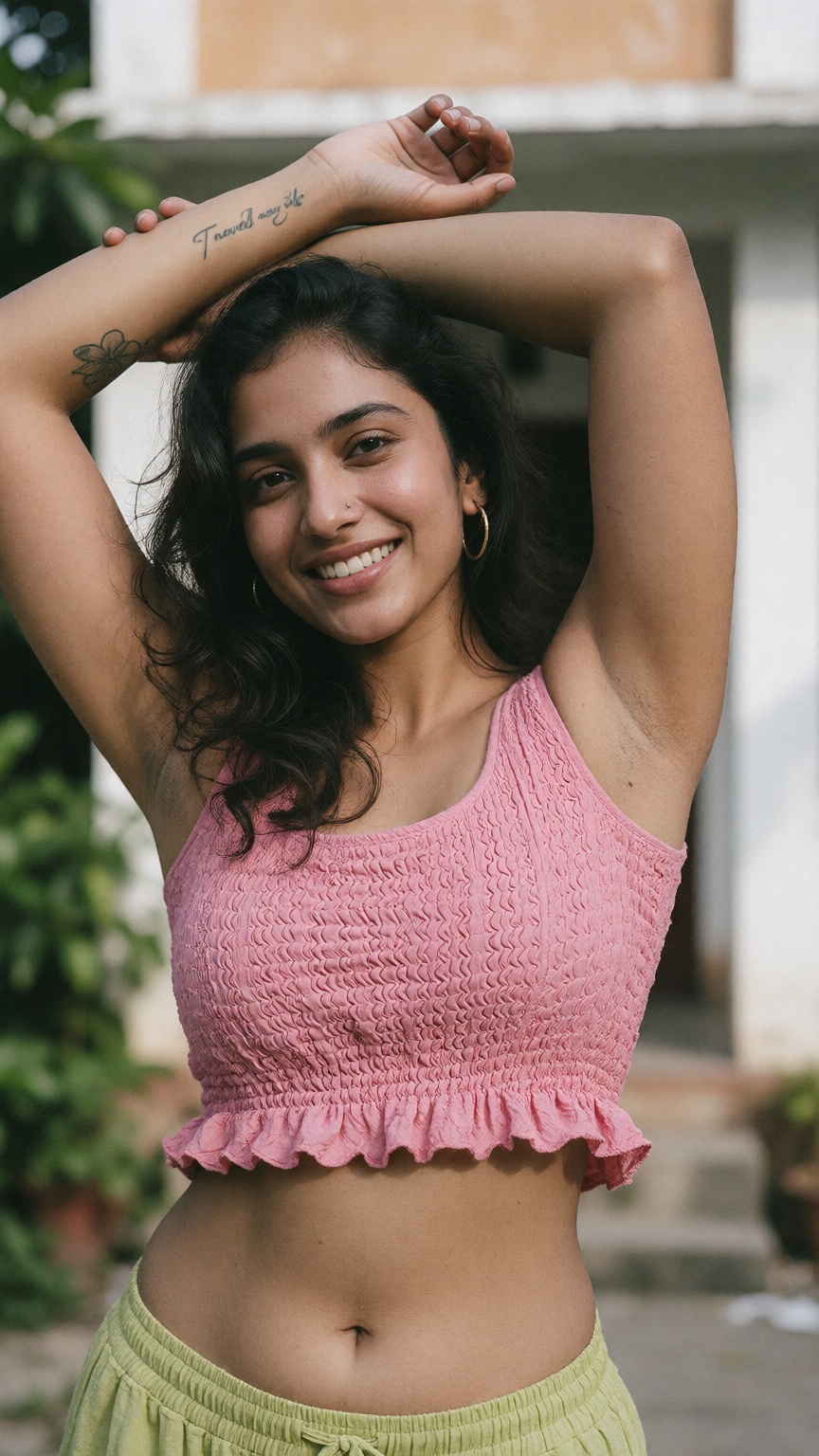 Photograph of a smiling young woman with medium brown skin and long,  wavy black hair. She is wearing a pink,  sleeveless...