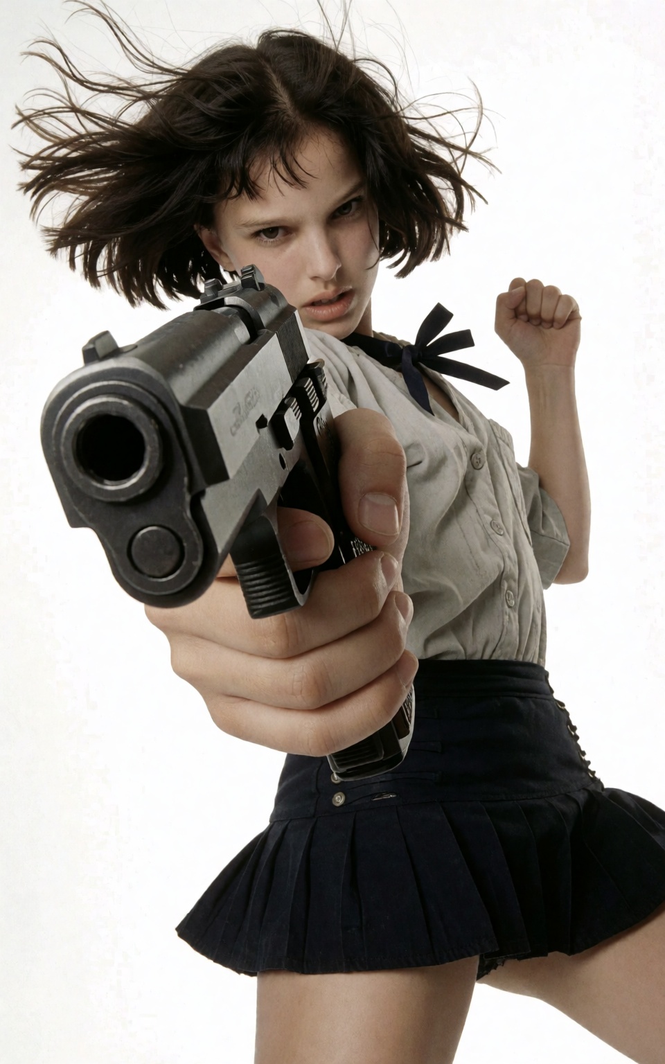 Low angle shot. A low-angle image of an intense young woman,  leaning slightly as she aims with a gun. She has wind-blown...