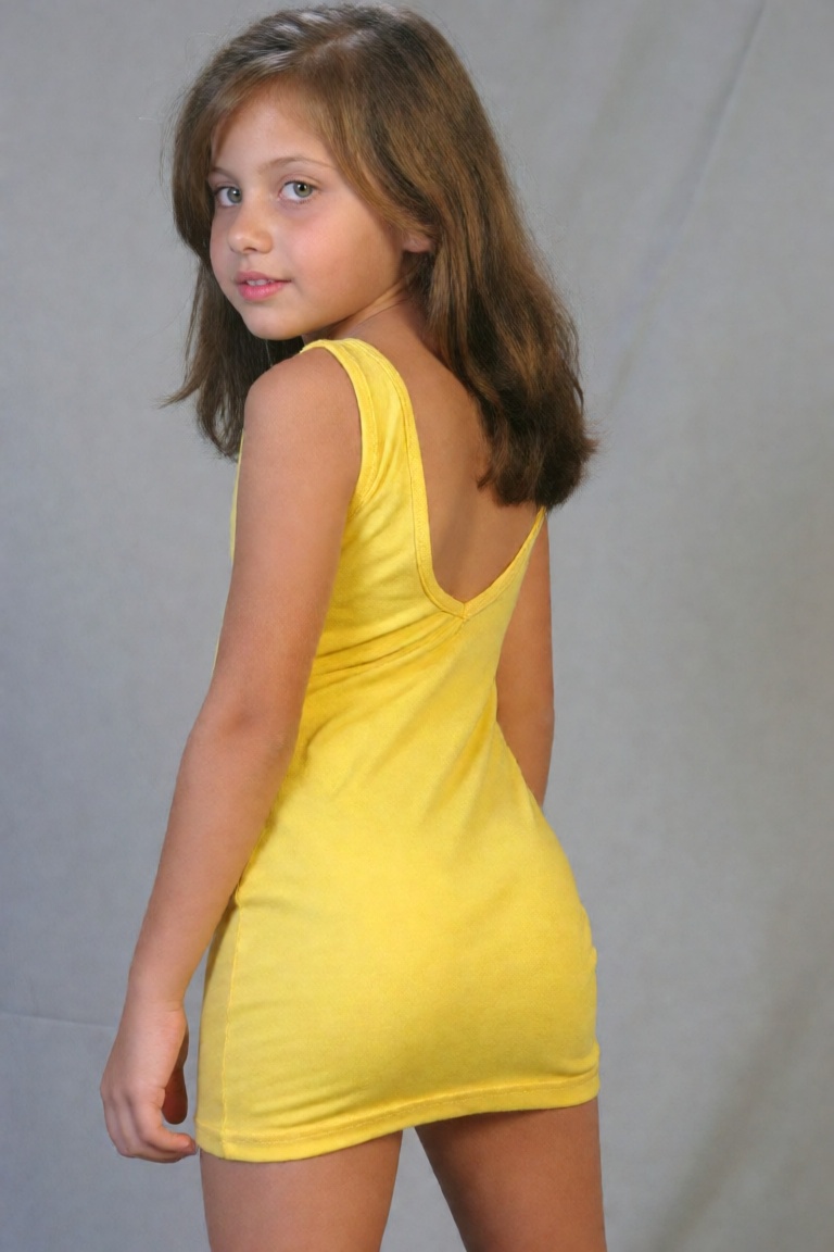 A young girl is wearing a short poleline yellow dress that hughs her body like a second sking,  the dress ends just above...