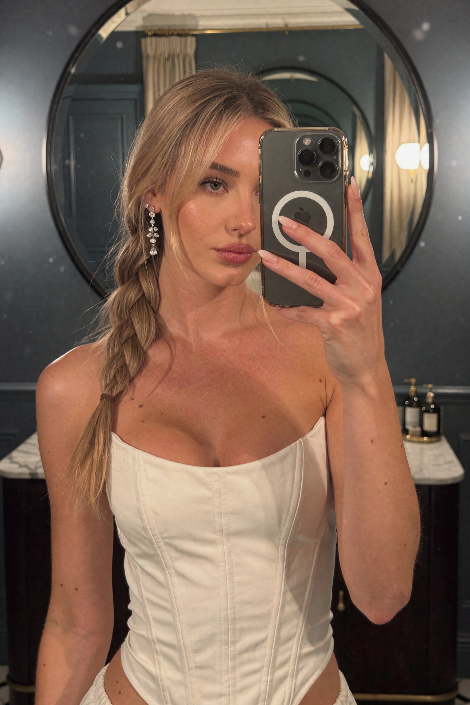 Candid smartphone mirror selfie of an ***** woman in a dim upscale interior,  chest-up framing. Blonde hair styled in a lo...