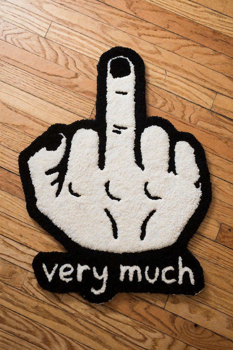 a fluffy carpet mat that represent a middle finger gesture on a hardwood floor. the words "very much" underneath the gestu...