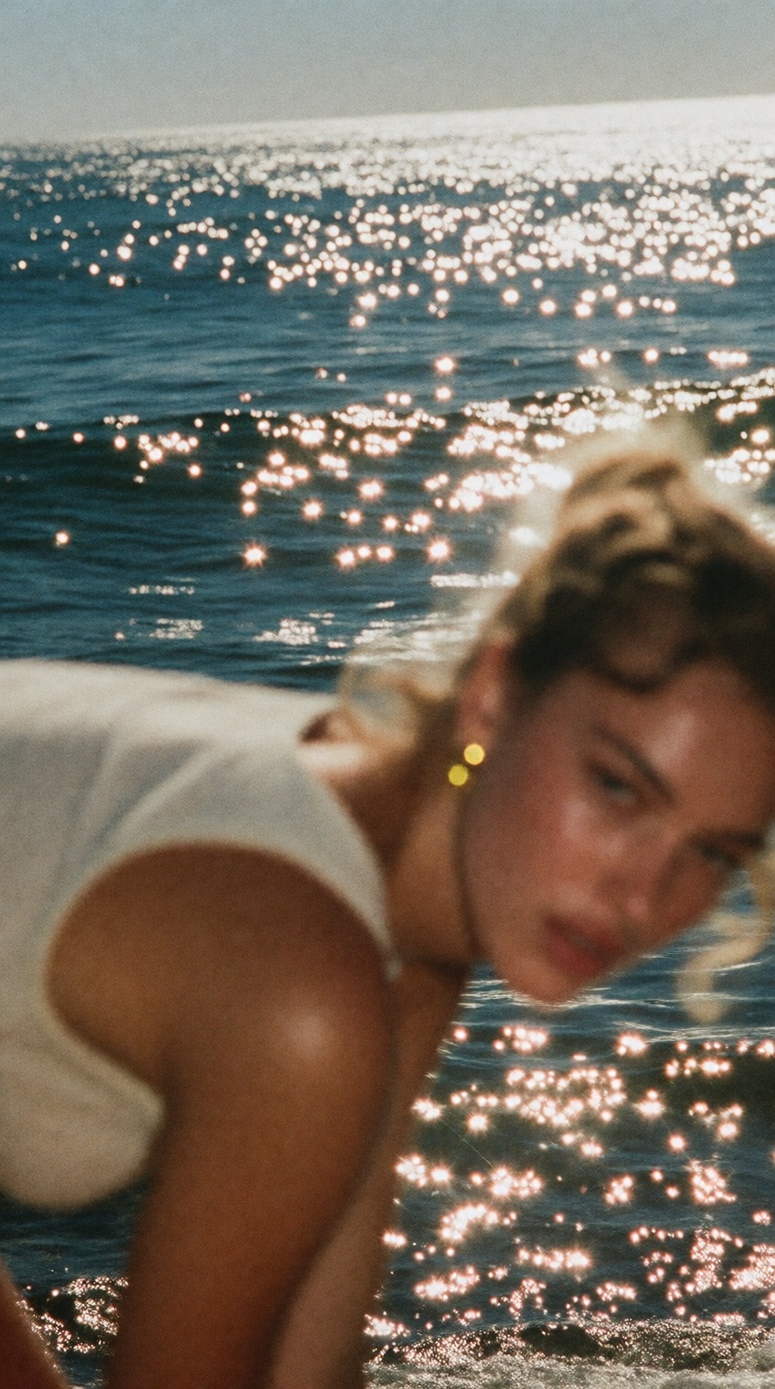 a sun-drenched scene captures a woman leaning forward in the foreground,  her form softly blurred against the crisp sparkl...
