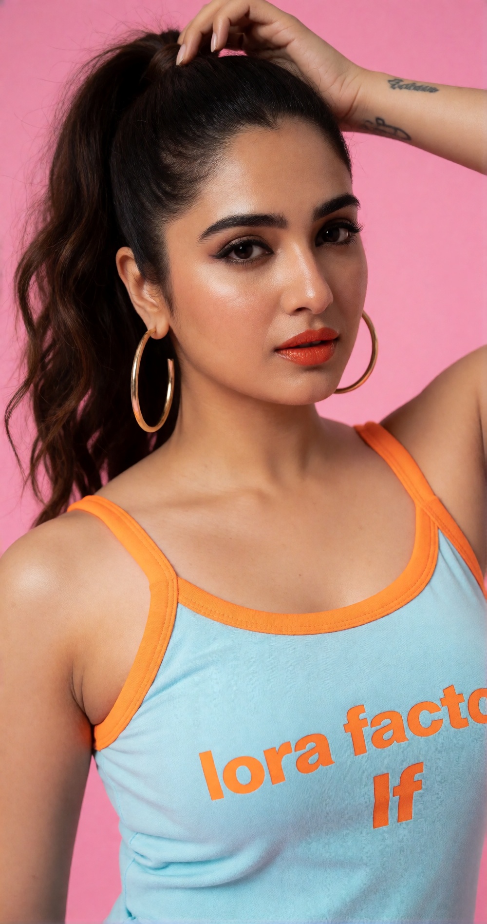 Photograph of a young woman with medium brown skin and long,  wavy dark brown hair,  styled in a high ponytail. She has we...