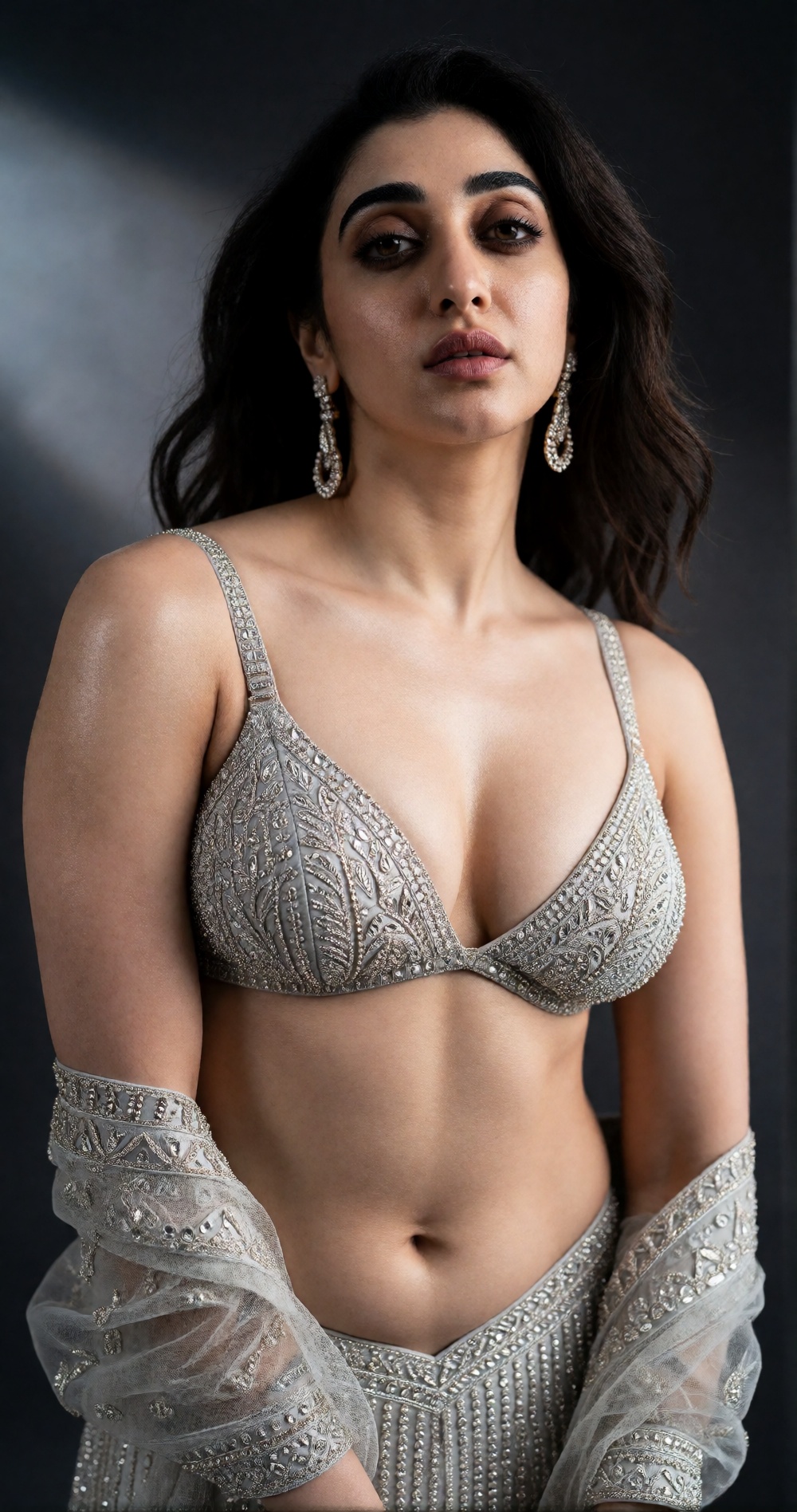 Photograph of a young woman with medium olive skin and dark brown,  shoulder-length wavy hair. She has well-defined eyebro...