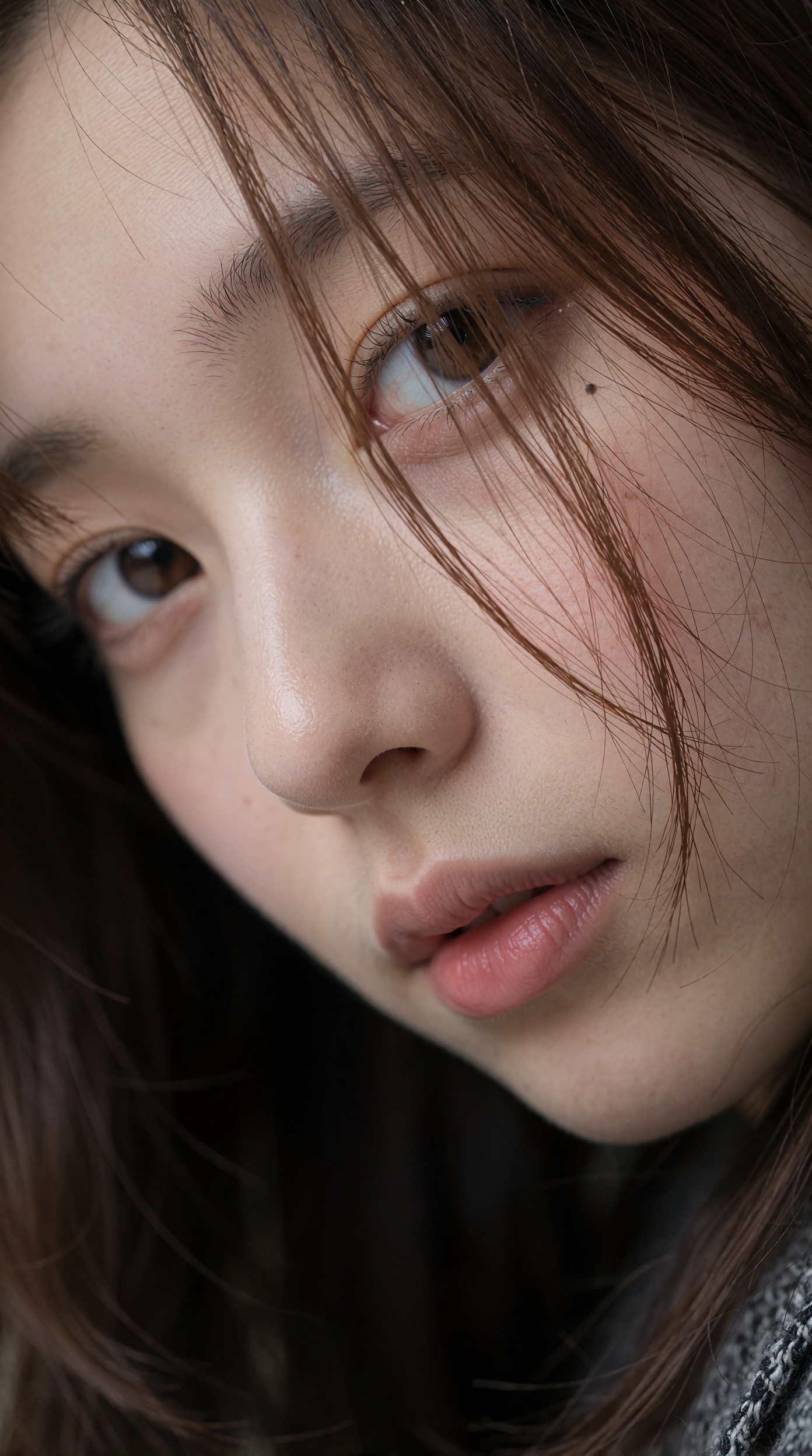 特写照片捕捉到一位年轻日本女子的脸微微向下倾斜,  她棕色的大眼睛以柔和的力度直视着观众,  淡棕色的细发部分遮住了她的脸 on Tensor.Art