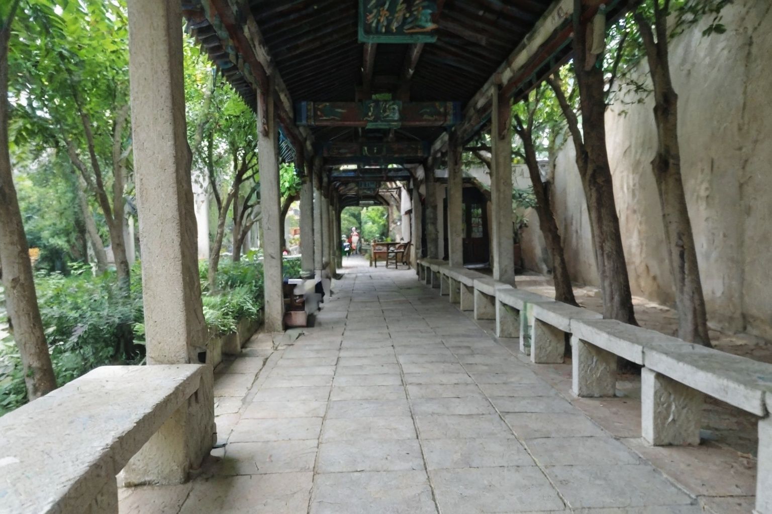 a long walkway with benches and trees in the background and a wall with a painting on it that says,<lora:her-000015:0.8>,