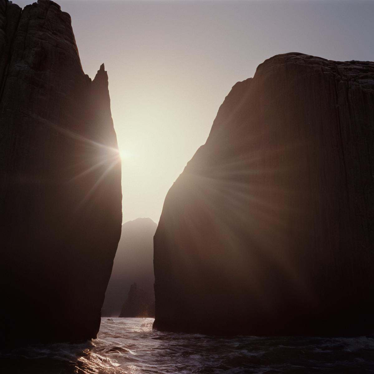 cinematic film still of a large rock formation with a sun shining through it,  outdoors,  sky on Tensor.Art
