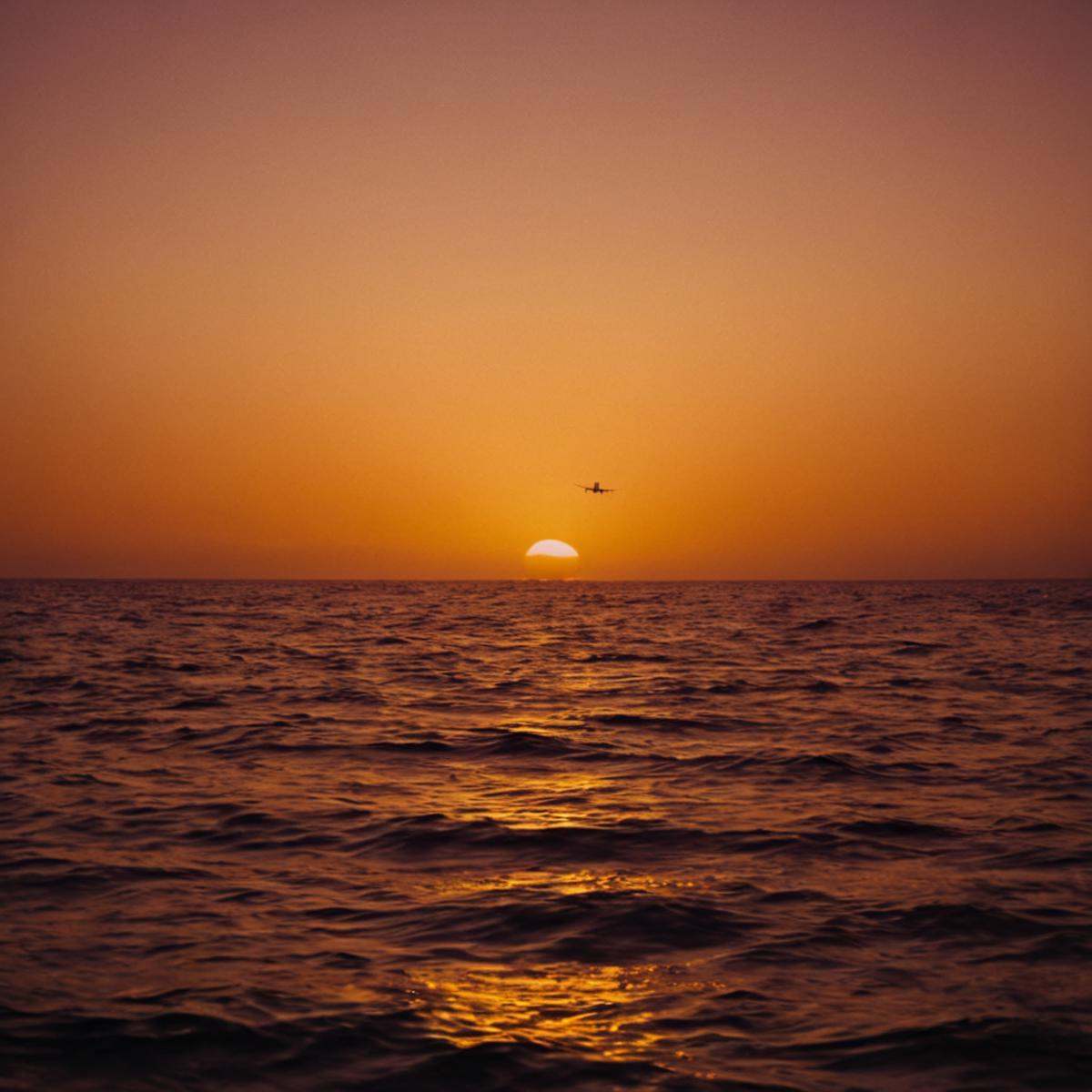 cinematic film still of In "Orange themed color",  a cinematic motion picture film of a sunset with a plane flying over th...