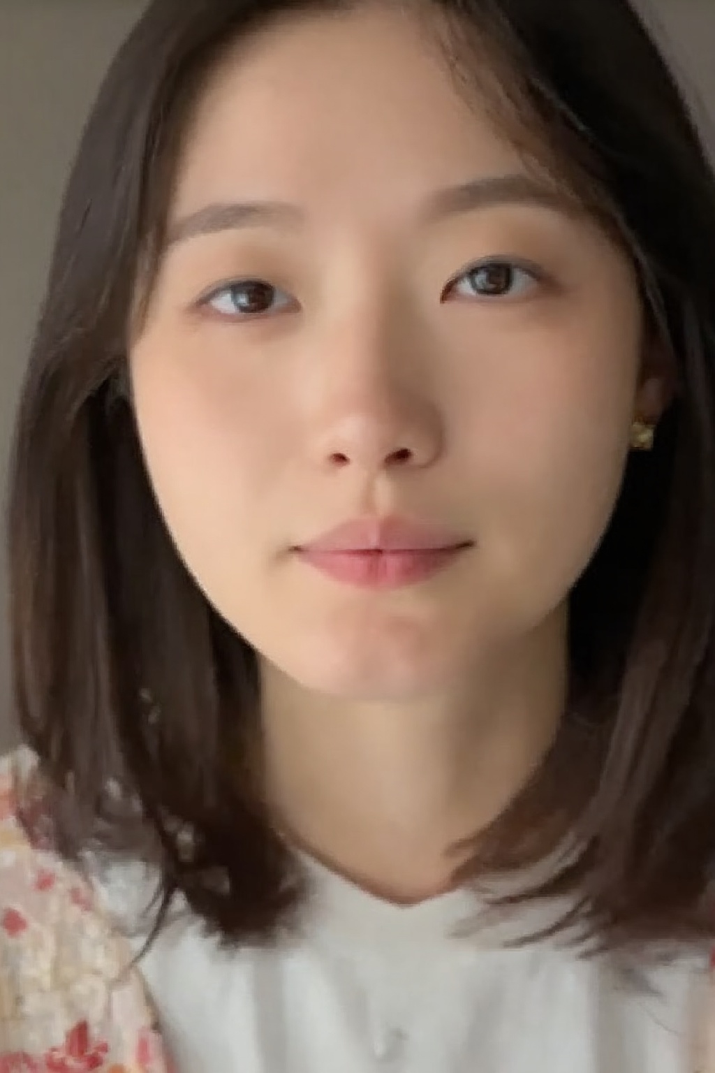 portrait of a young woman. she is looking up at the camera. her shoulder length brown hair frames her face. she is confide...