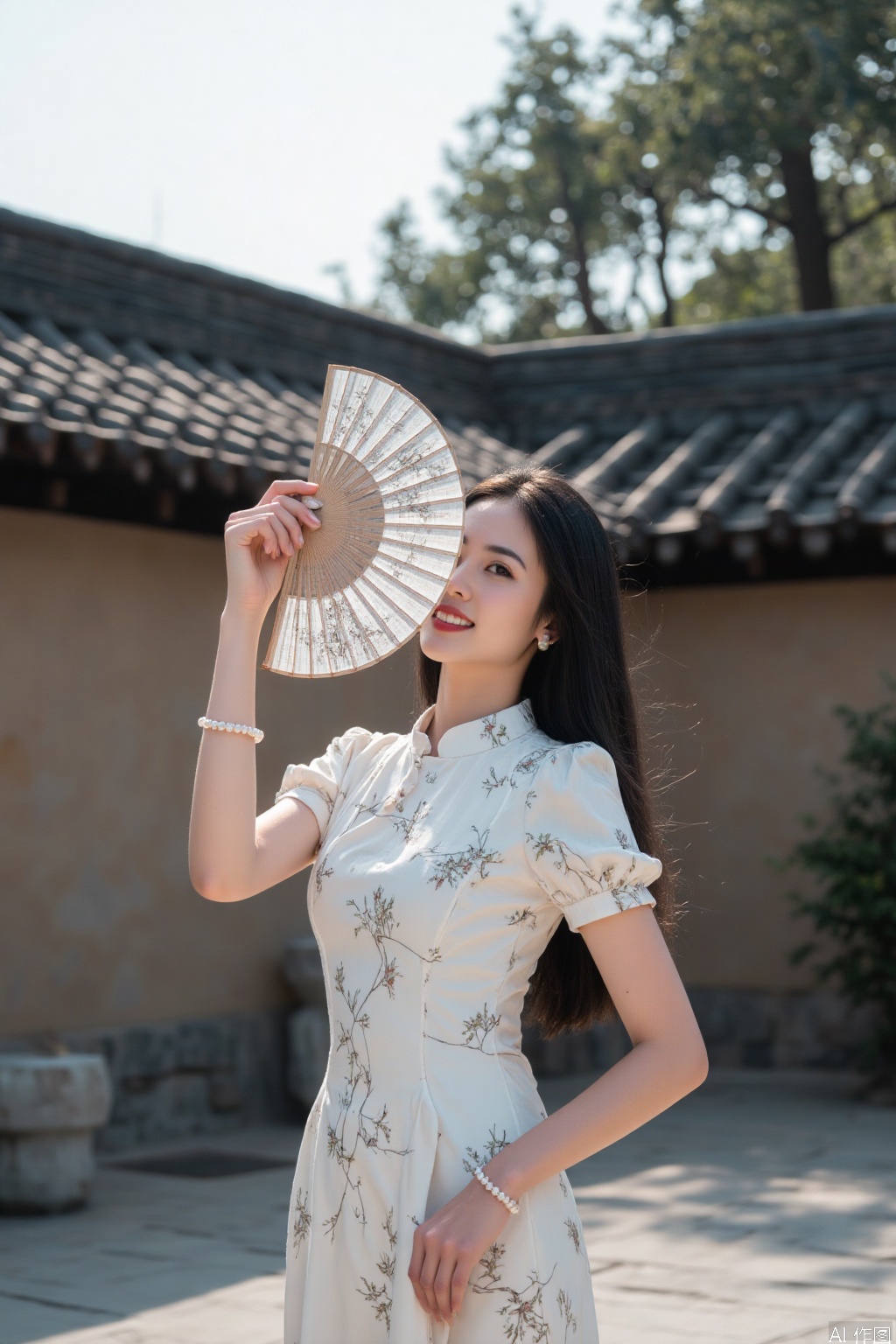 The image shows a woman standing outdoors, dressed in a traditional-style dress with floral patterns. She is holding a decorative fan with a delicate design, partially covering her face. Her hair is styled neatly, and she is wearing pearl bracelets on her left wrist. The background features a traditional architectural structure with a tiled roof and stone walls, suggesting a historical or cultural setting. The overall atmosphere is serene and elegant, with a focus on traditional aesthetics.
