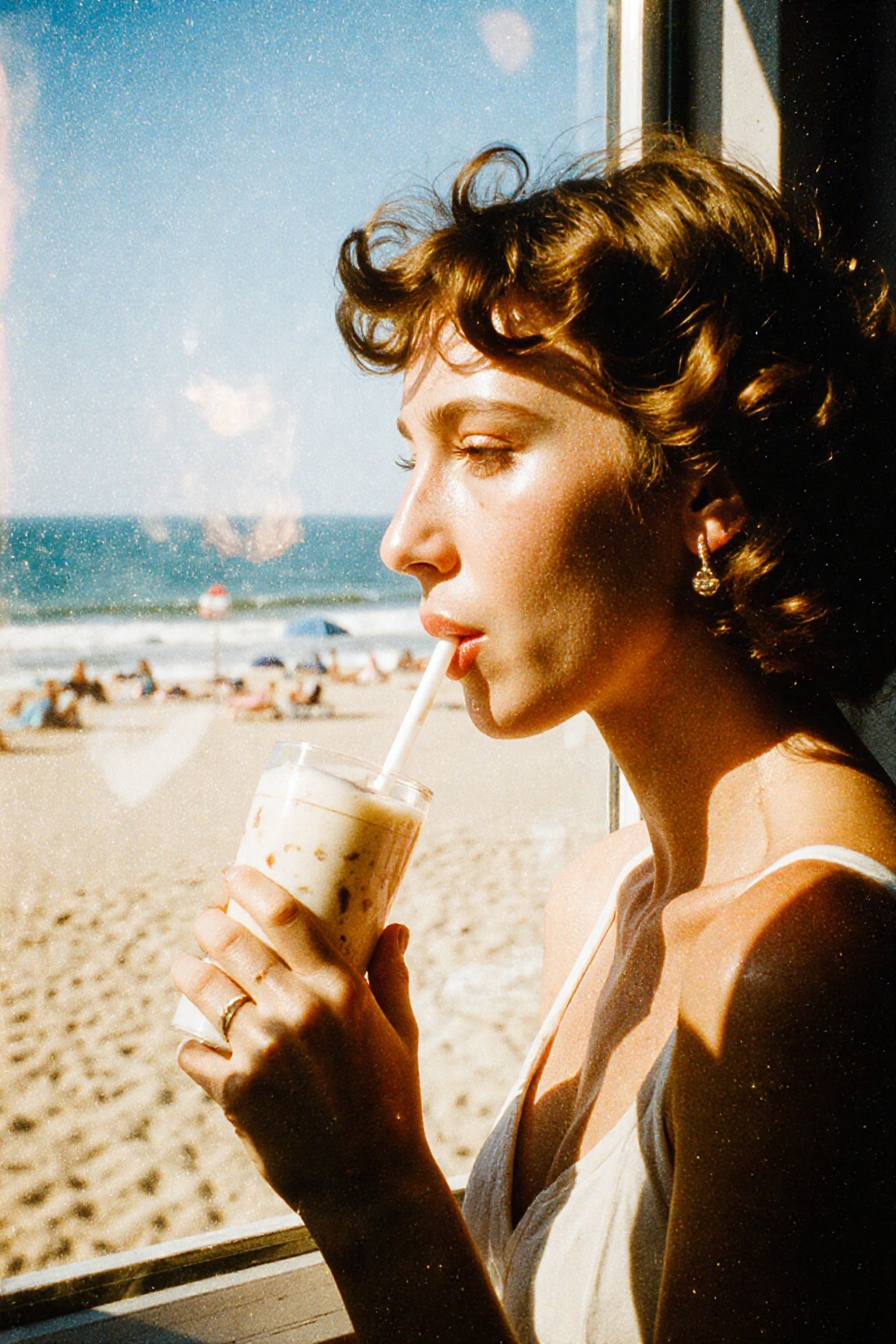 A side-profile shot of a woman with curly hair drinking a milkshake through a straw. She is viewed through a window,  with...