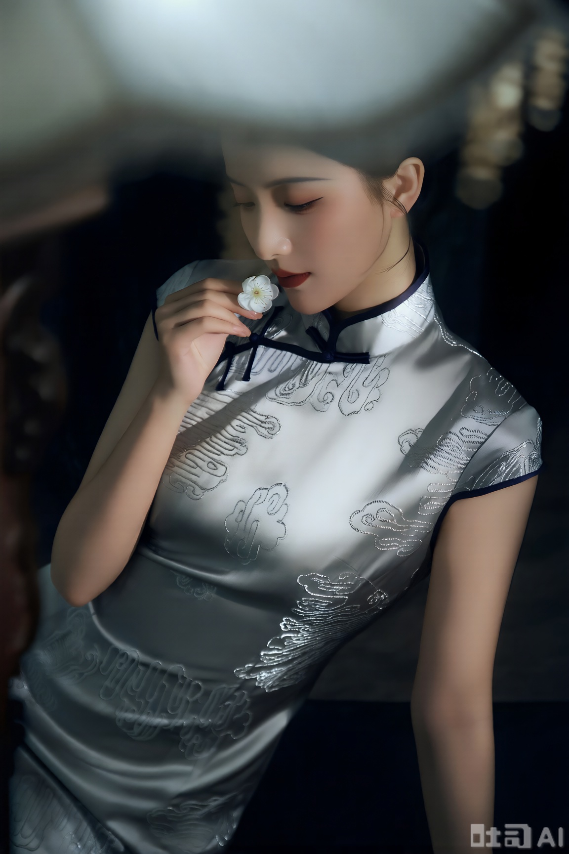 优雅东方女性身着绣有银线云纹的新中式旗袍,领口与下摆镶着墨色滚边,气质清冷。整体为氛围感电影写真风格,搭配冷调的室内顶光,光线在人物面部形成轻微明暗对比,以朦胧的柔光渲染增添梦幻感,色彩以银灰与墨黑为主,尽显高级感,采用近景构图,从略微俯拍的视角聚焦人物低头轻嗅白梅的瞬间,画面静谧又动人。