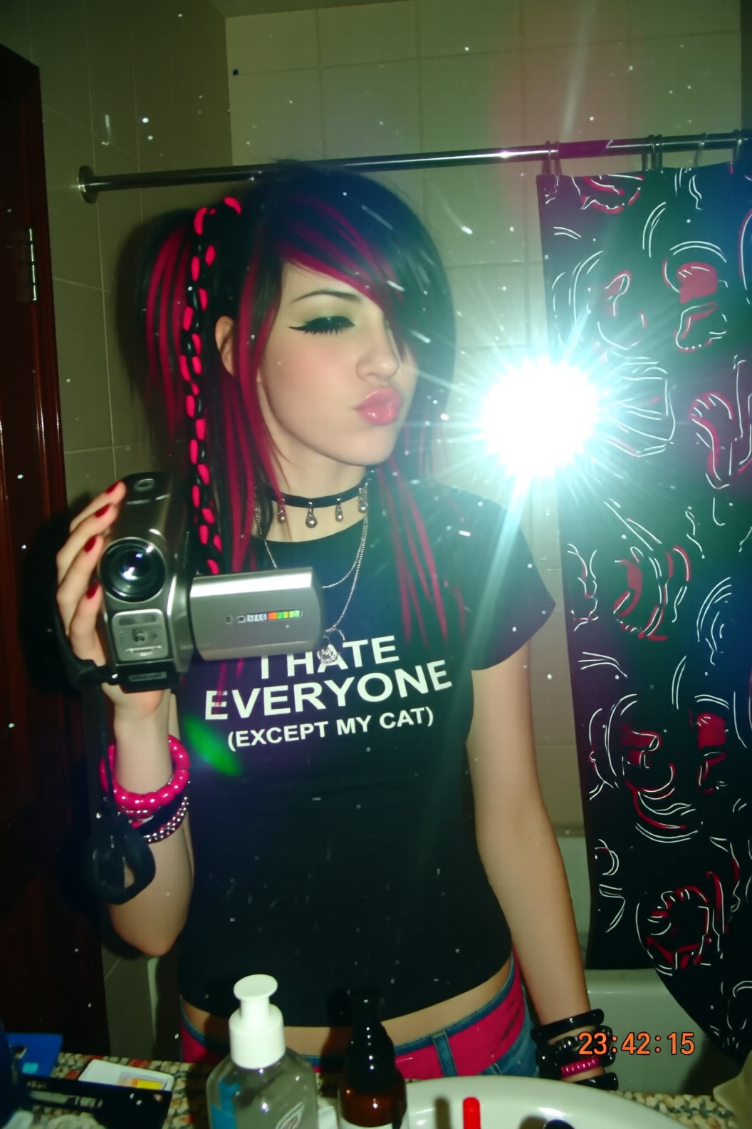 A low-resolution,  pixelated camcorder video still with a harsh,  blinding flash reflecting off a dirty bathroom mirror. A...