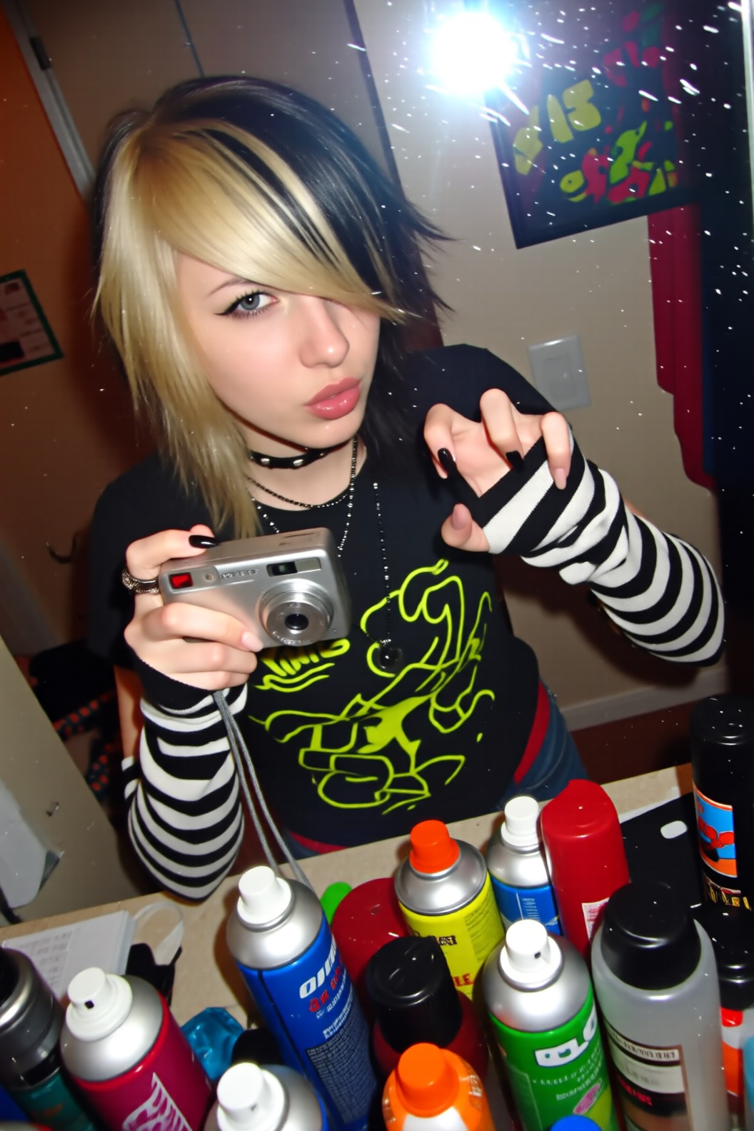 A high-angle mirror selfie taken by a girl with teased,  choppy "scene" hair featuring blonde and black "coon tail" extens...