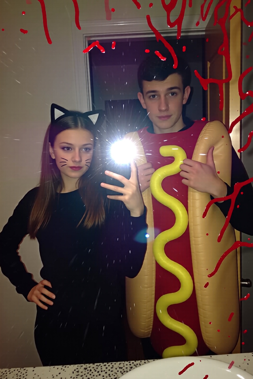 A mirror selfie taken by a girl wearing simple black clothes and "cat ears" on a headband,  with whiskers drawn on her fac...
